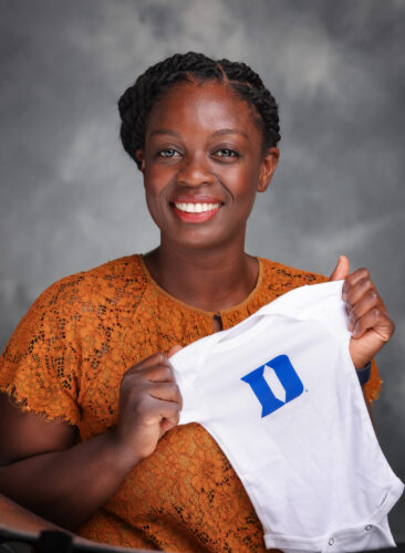 young professional womanizing holding a baby 'onsie' with the Duke logo on it